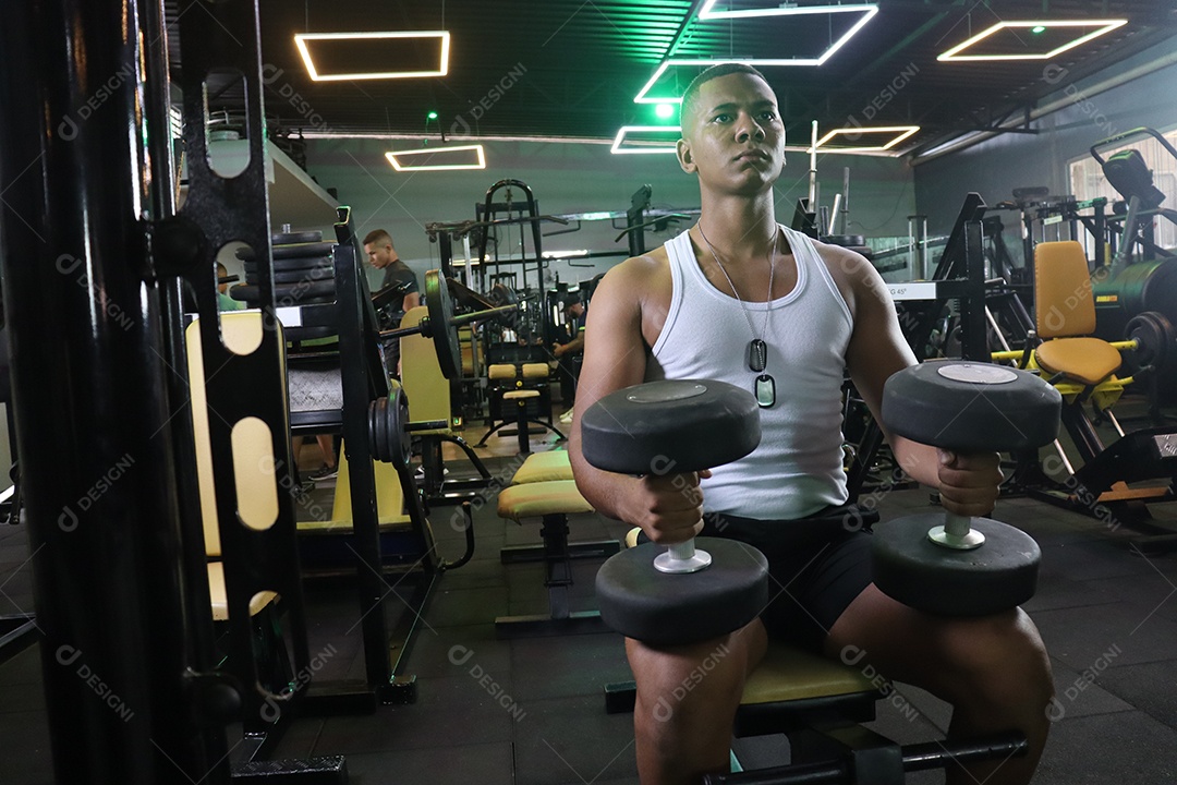 Belo homem fazendo exercicíos sobre uma academia