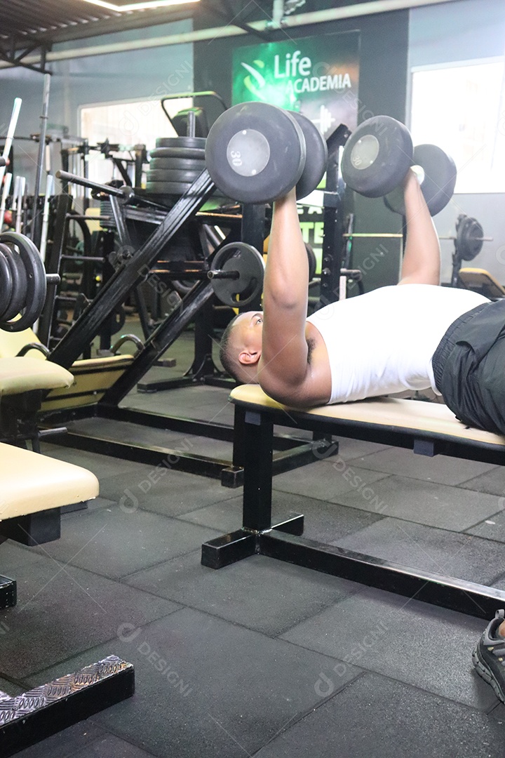 Belo homem fazendo exercicíos sobre uma academia