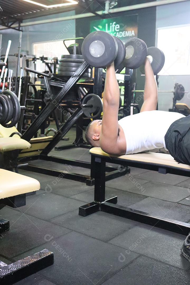 Belo homem fazendo exercicíos sobre uma academia