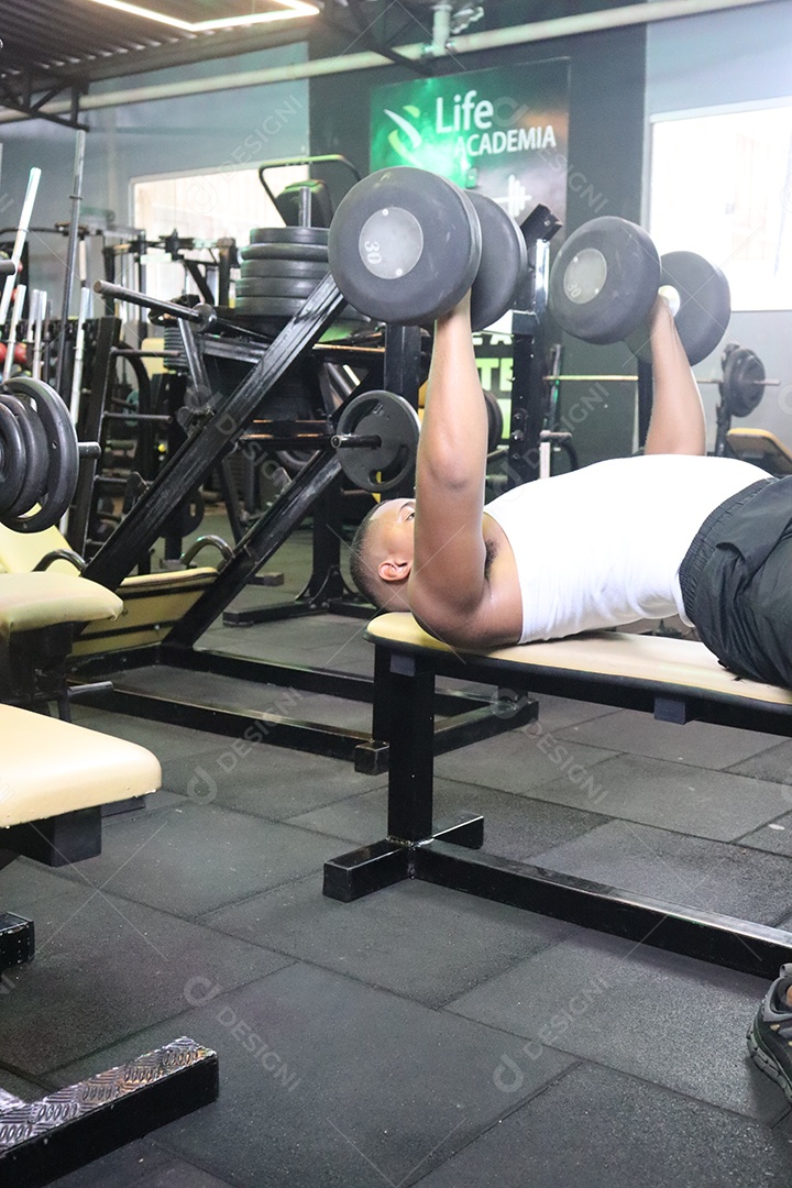 Belo homem fazendo exercicíos sobre uma academia