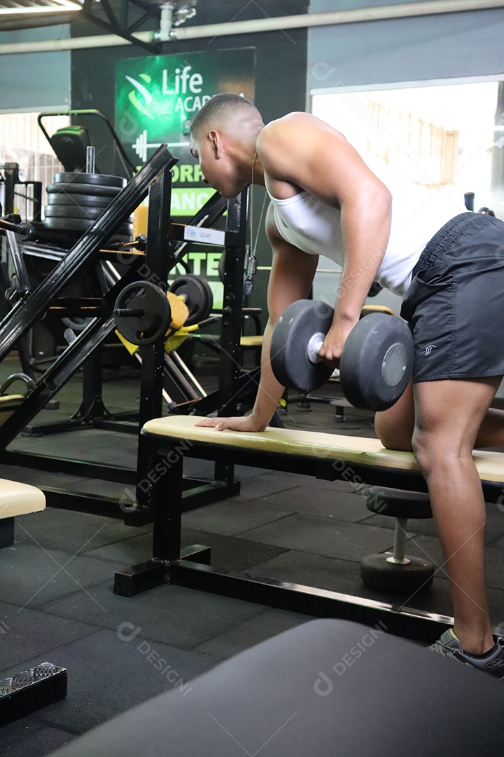 Belo homem fazendo exercicíos sobre uma academia