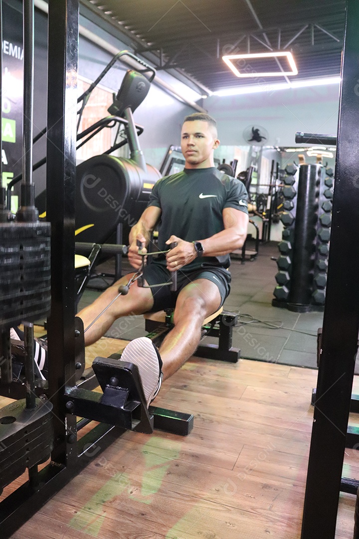 Belo homem fazendo exercicíos sobre uma academia