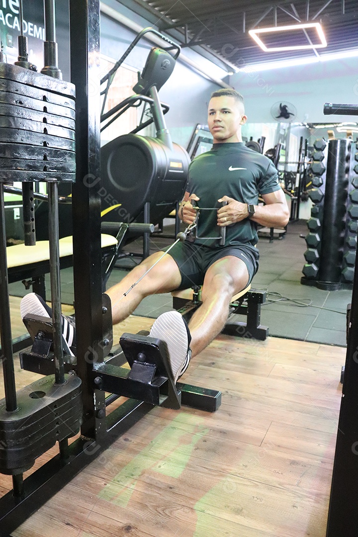 Belo homem fazendo exercicíos sobre uma academia