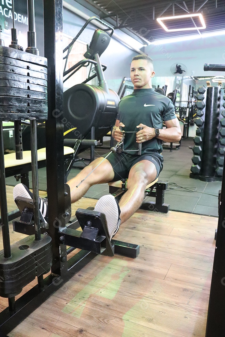 Belo homem fazendo exercicíos sobre uma academia