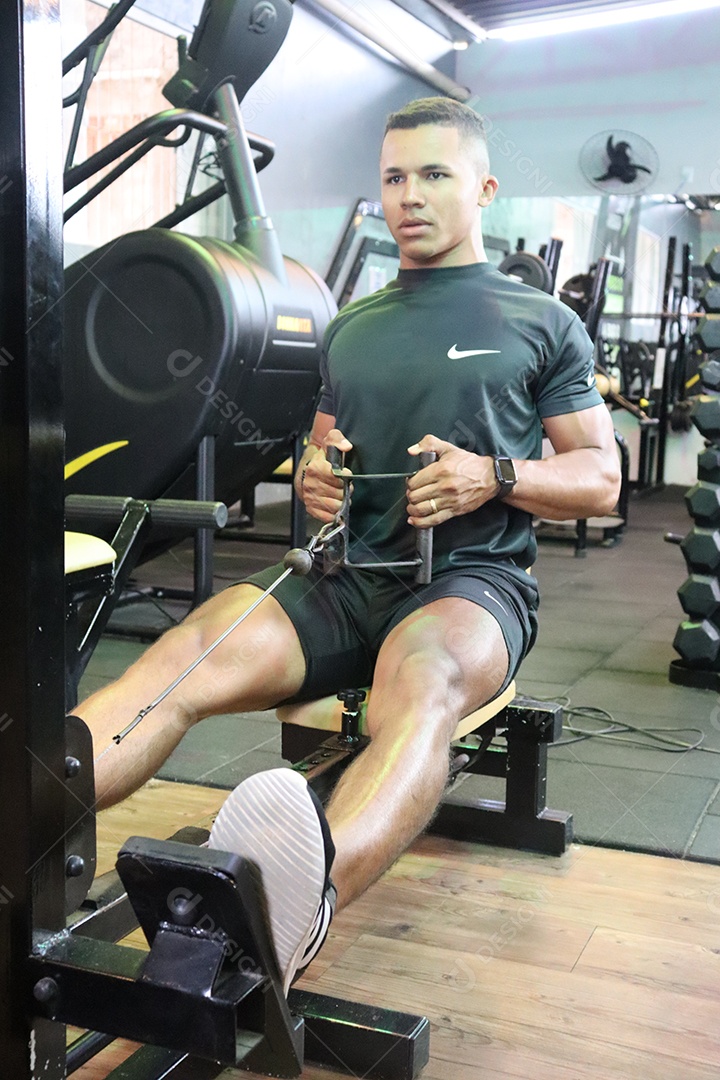 Belo homem fazendo exercicíos sobre uma academia