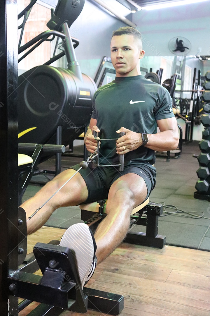 Belo homem fazendo exercicíos sobre uma academia