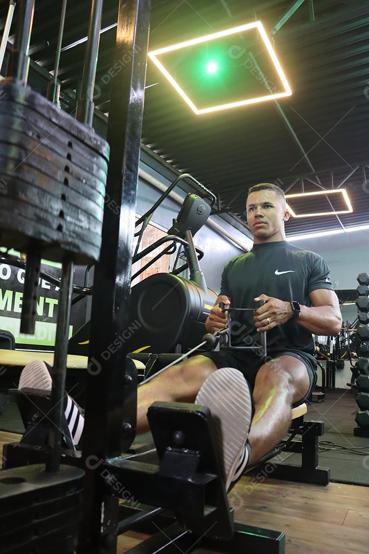 Belo homem fazendo exercicíos sobre uma academia