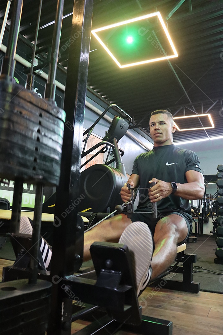 Belo homem fazendo exercicíos sobre uma academia