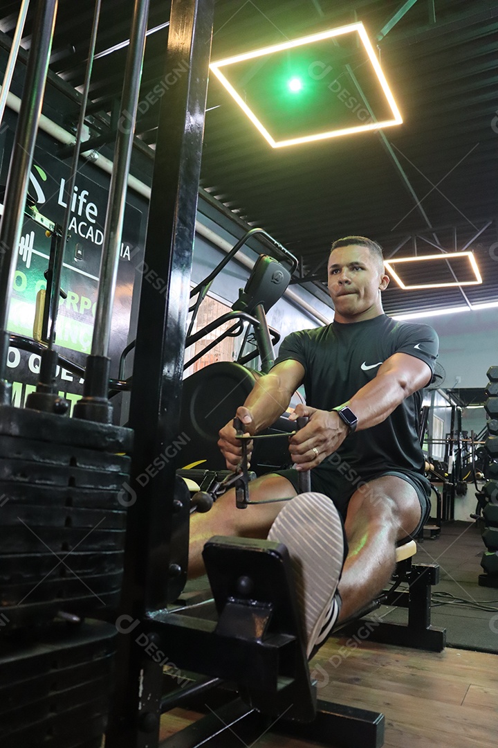 Belo homem fazendo exercicíos sobre uma academia