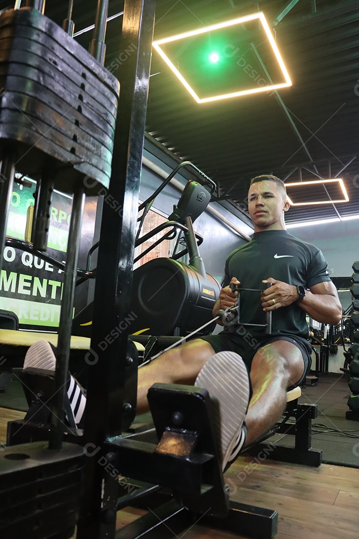 Belo homem fazendo exercicíos sobre uma academia