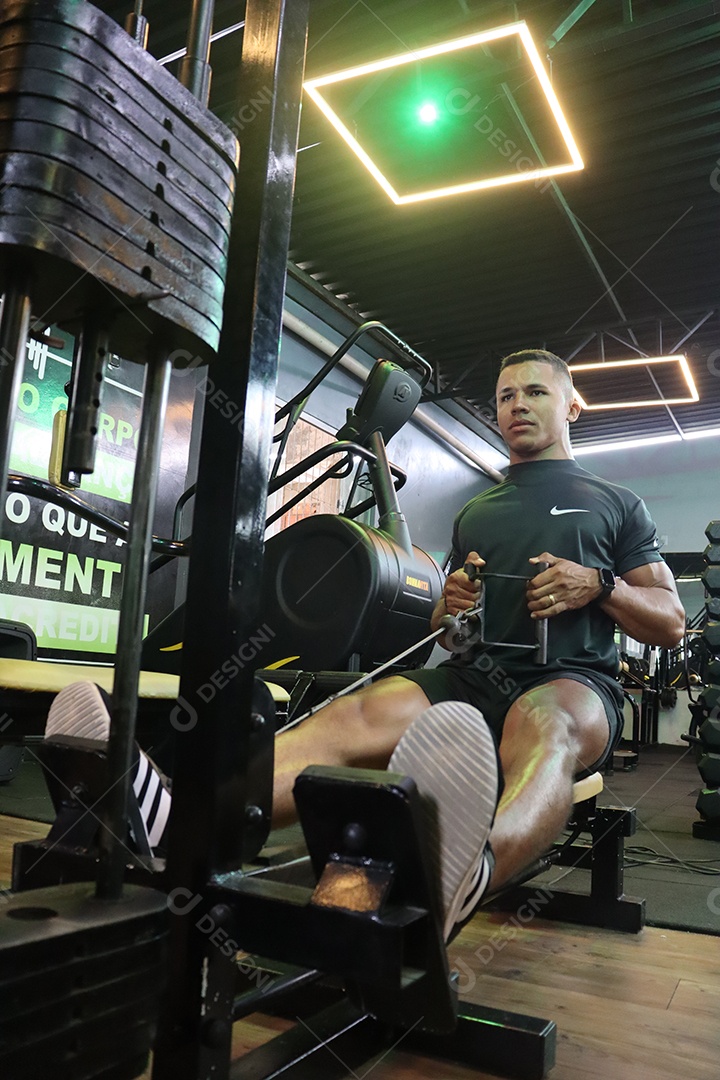 Belo homem fazendo exercicíos sobre uma academia