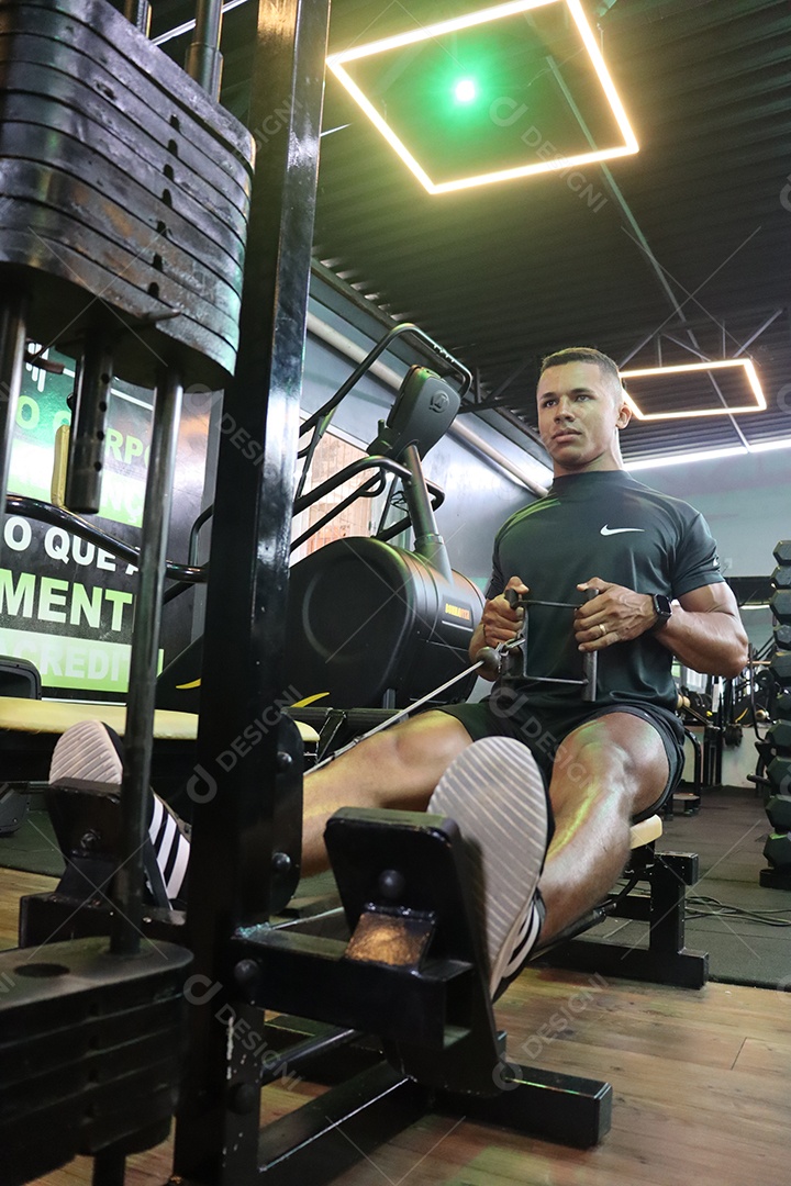 Belo homem fazendo exercicíos sobre uma academia