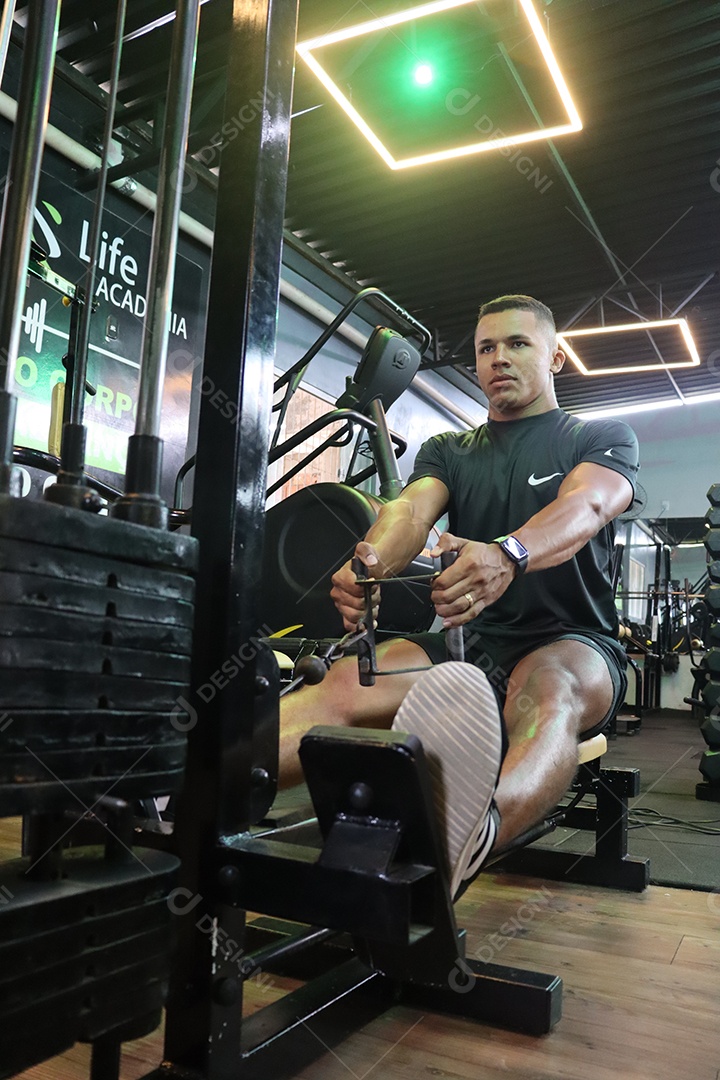 Belo homem fazendo exercicíos sobre uma academia