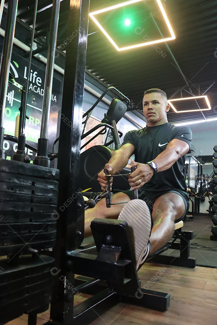 Belo homem fazendo exercicíos sobre uma academia