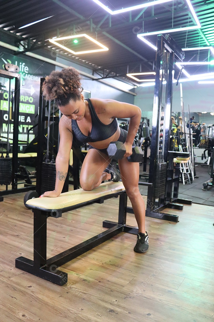 Bela mulher fazendo exercicíos sobre uma academia