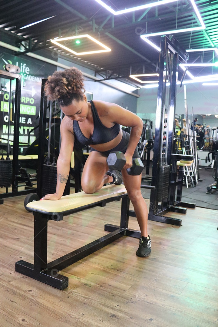 Bela mulher fazendo exercicíos sobre uma academia