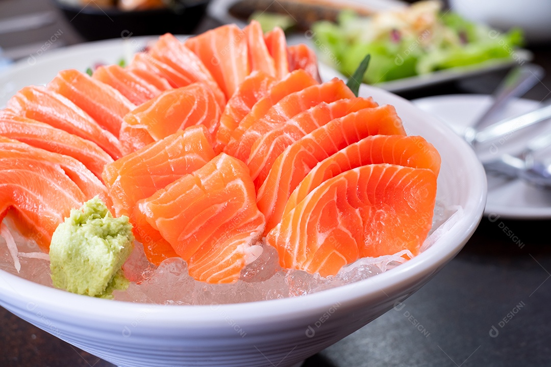 Fatia de salmão cru ou sashimi de salmão e wasabi no estilo japonês servido fresco no gelo em uma tigela branca