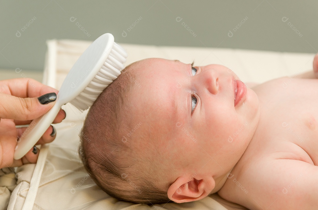 Mãe penteando o cabelo do bebê recém nascido na cama