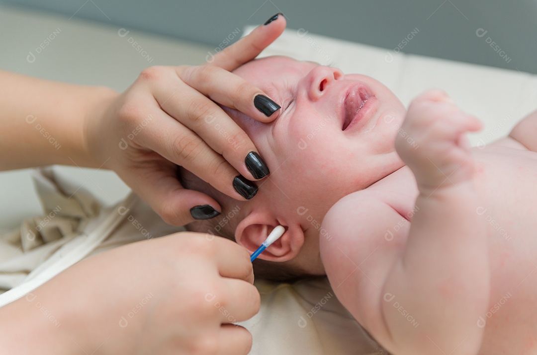 Orelha de recém nascido sendo limpa com cotonete