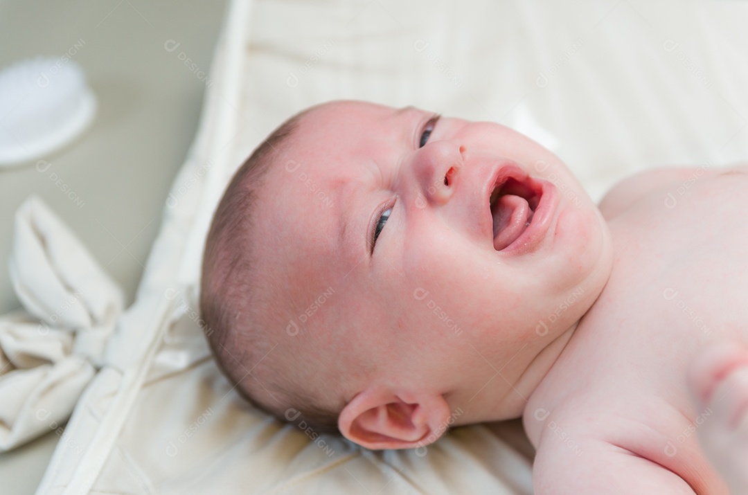 Bebê recém nascido chorando deitado na cama