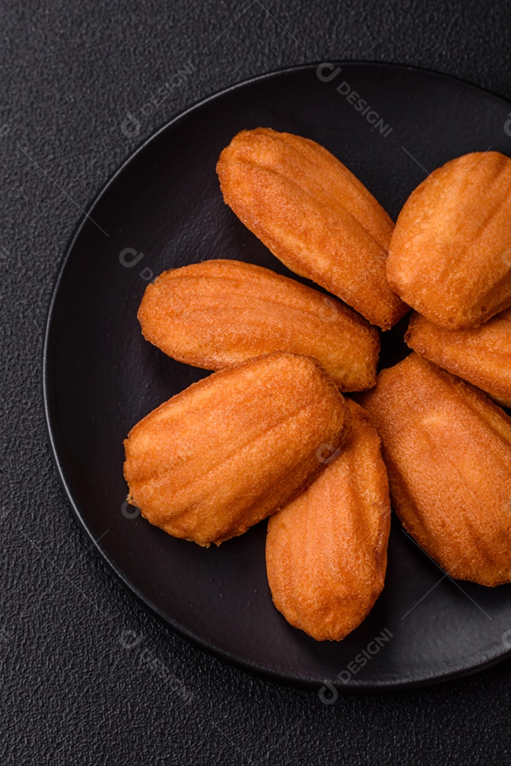 Biscoitos tradicionais de madeleine francesa com sabor de nozes fundo escuro de concreto