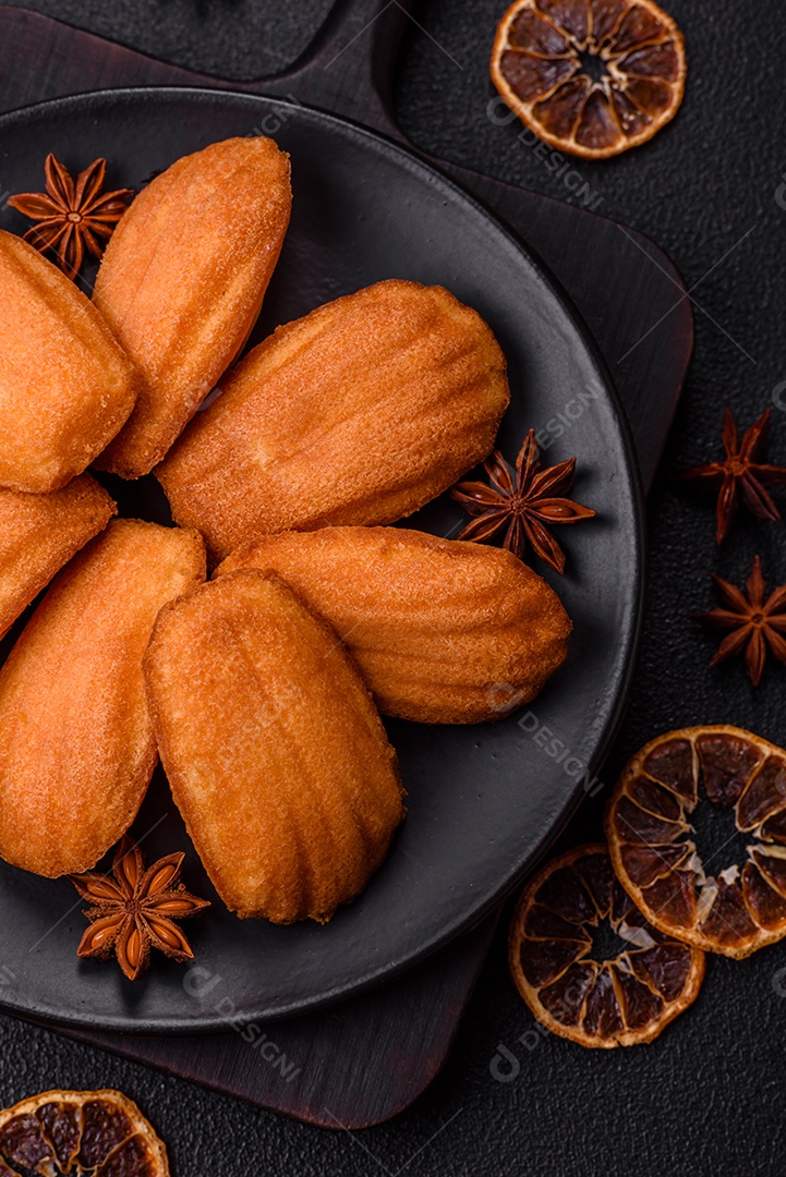 Biscoitos tradicionais de madeleine francesa com sabor de nozes fundo escuro de concreto