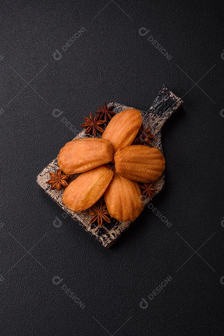 Biscoitos tradicionais de madeleine francesa com sabor de nozes fundo escuro de concreto