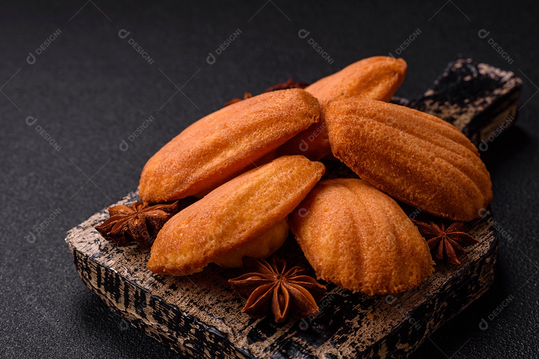 Biscoitos tradicionais de madeleine francesa com sabor de nozes fundo escuro de concreto