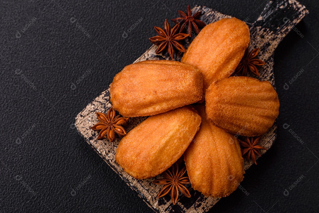 Biscoitos tradicionais de madeleine francesa com sabor de nozes fundo escuro de concreto