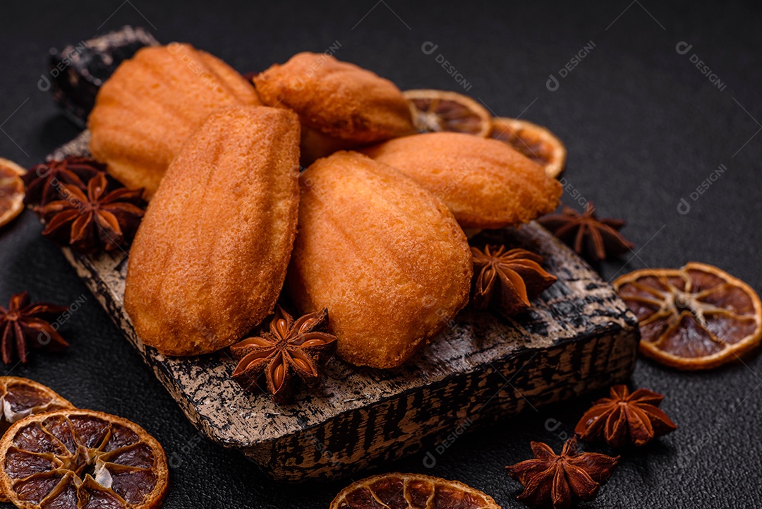 Biscoitos tradicionais de madeleine francesa com sabor de nozes fundo escuro de concreto