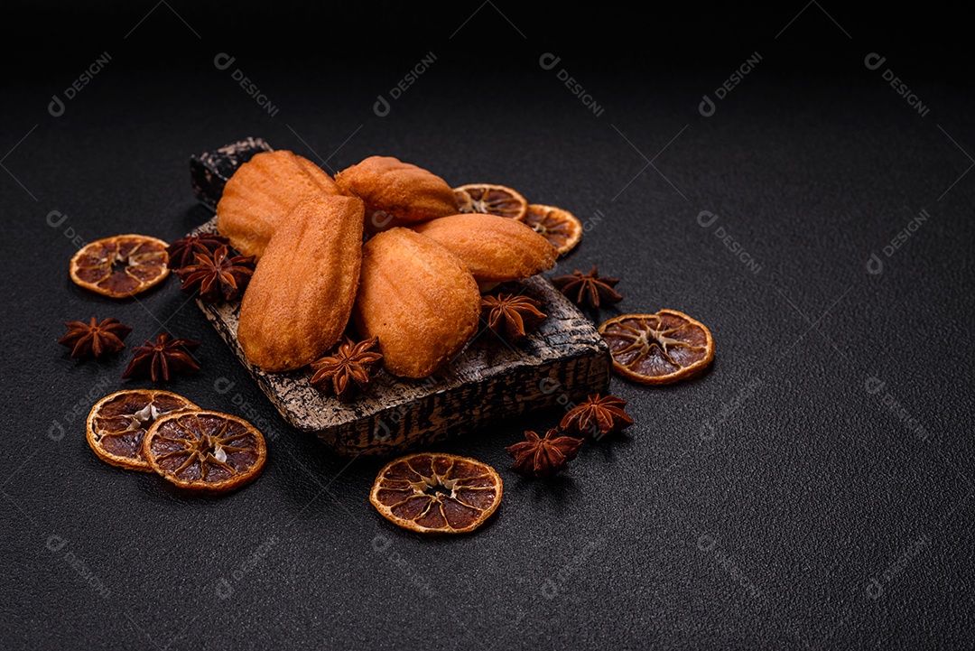 Biscoitos tradicionais de madeleine francesa com sabor de nozes fundo escuro de concreto