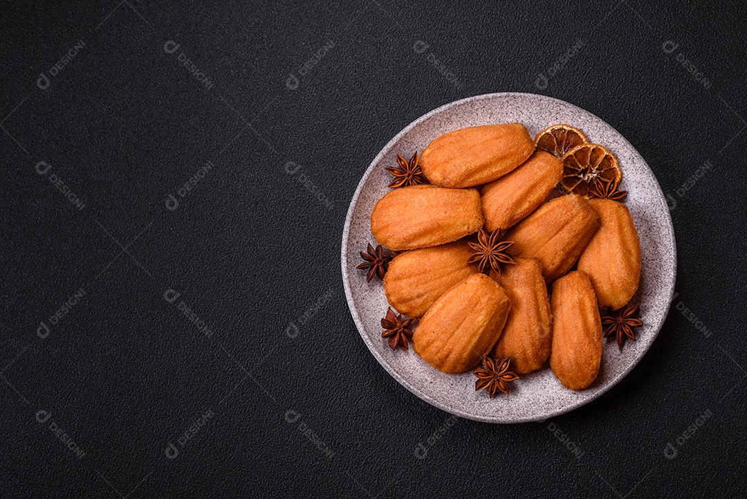 Biscoitos tradicionais de madeleine francesa com sabor de nozes fundo escuro de concreto