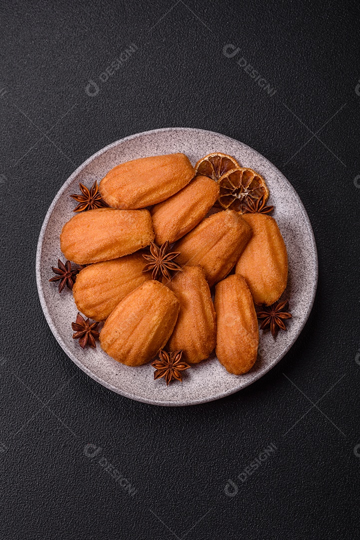 Biscoitos tradicionais de madeleine francesa com sabor de nozes fundo escuro de concreto