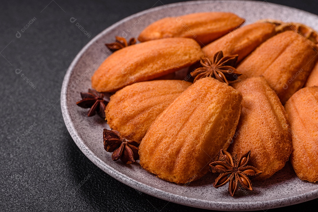 Biscoitos tradicionais de madeleine francesa com sabor de nozes fundo escuro de concreto