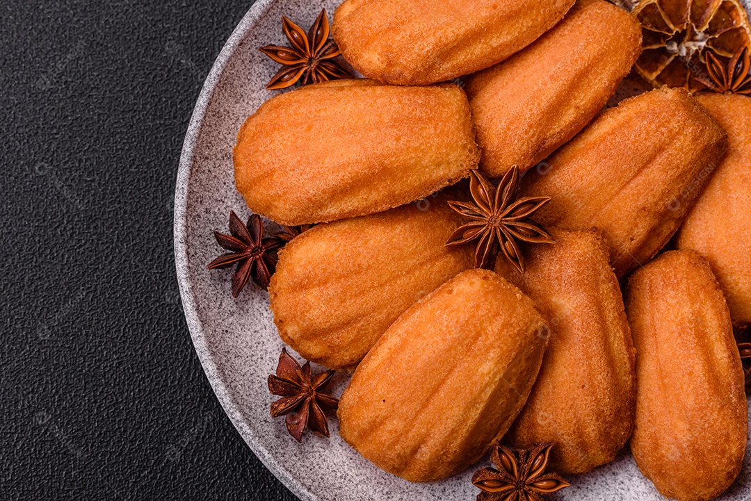 Biscoitos tradicionais de madeleine francesa com sabor de nozes fundo escuro de concreto