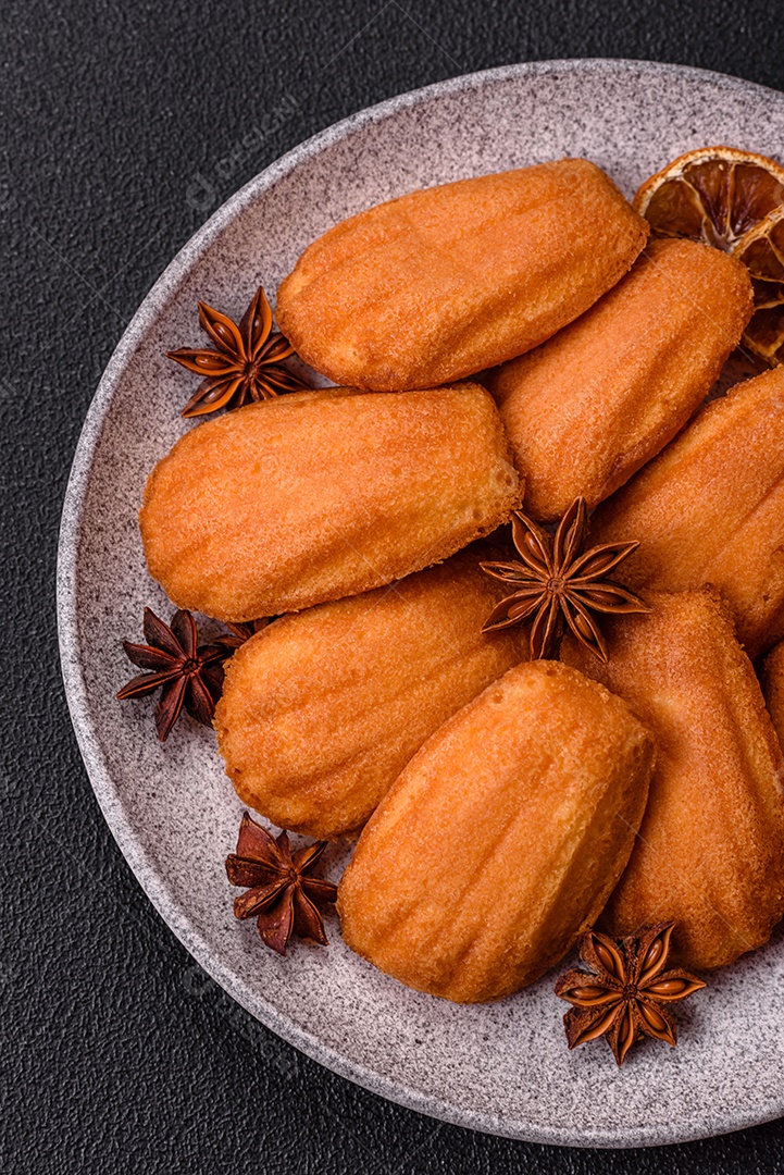 Biscoitos tradicionais de madeleine francesa com sabor de nozes fundo escuro de concreto