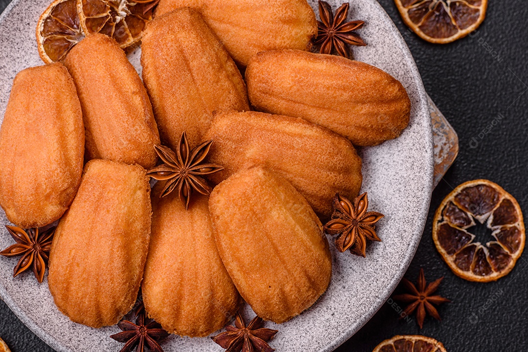 Biscoitos tradicionais de madeleine francesa com sabor de nozes fundo escuro de concreto