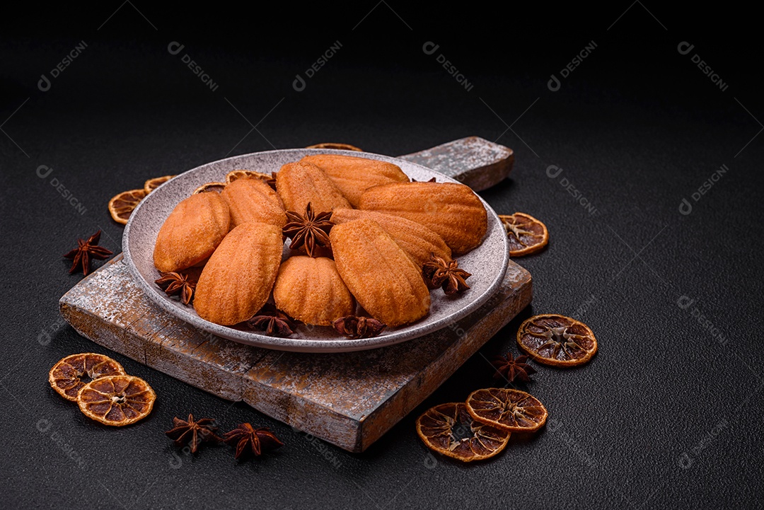 Biscoitos tradicionais de madeleine francesa com sabor de nozes fundo escuro de concreto