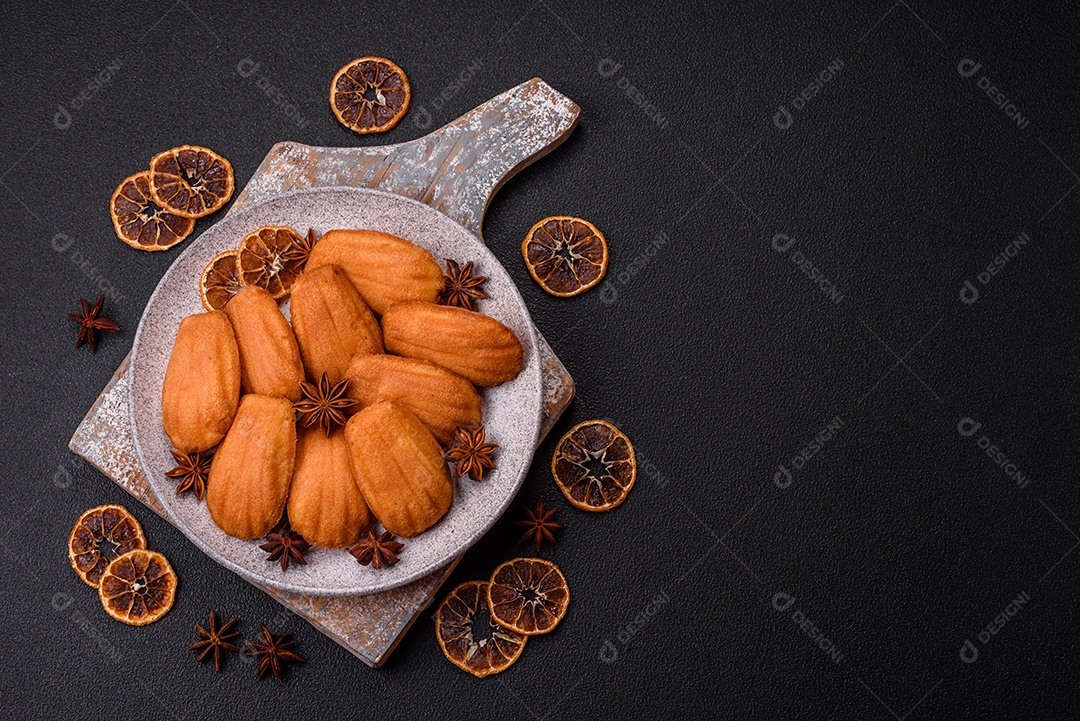 Biscoitos tradicionais de madeleine francesa com sabor de nozes fundo escuro de concreto