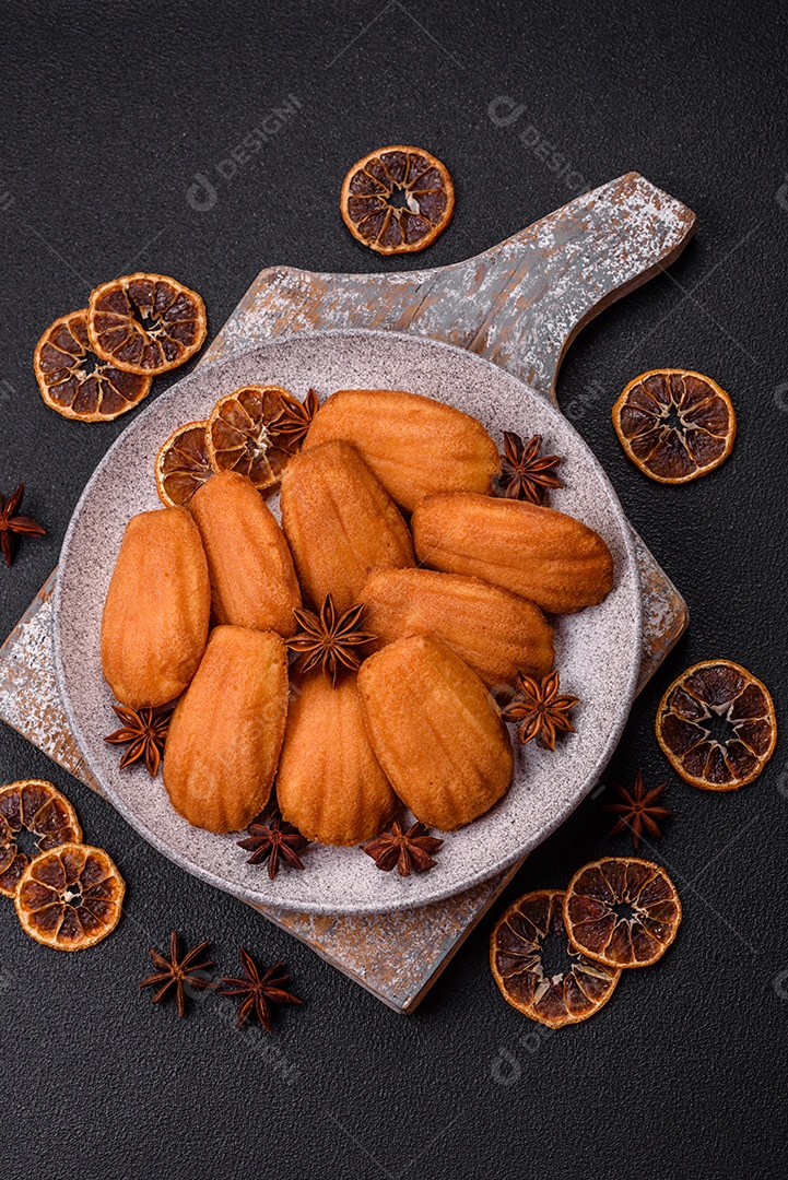 Biscoitos tradicionais de madeleine francesa com sabor de nozes fundo escuro de concreto