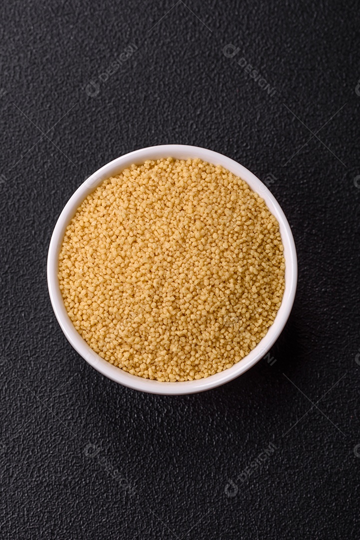 Grãos de cuscuz de mingau de trigo em um fundo escuro de concreto