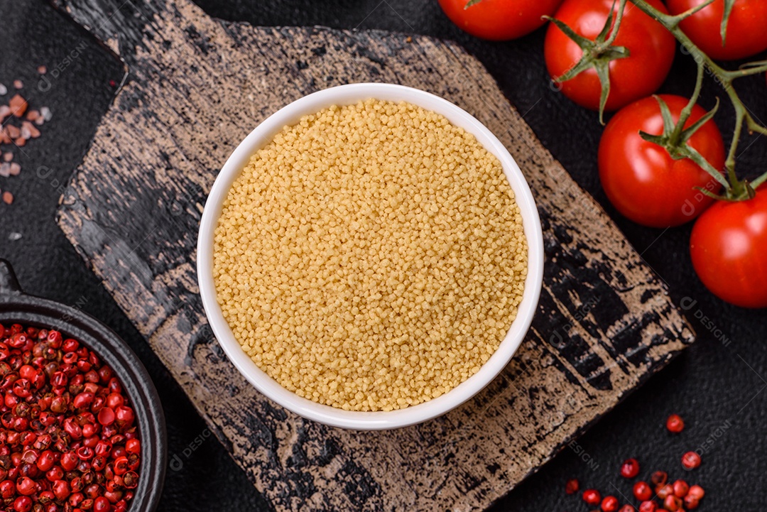 Grãos de cuscuz de mingau de trigo em um fundo escuro de concreto