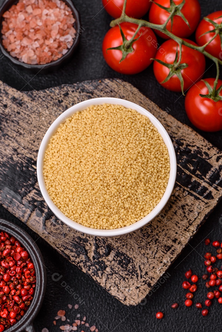 Grãos de cuscuz de mingau de trigo em um fundo escuro de concreto