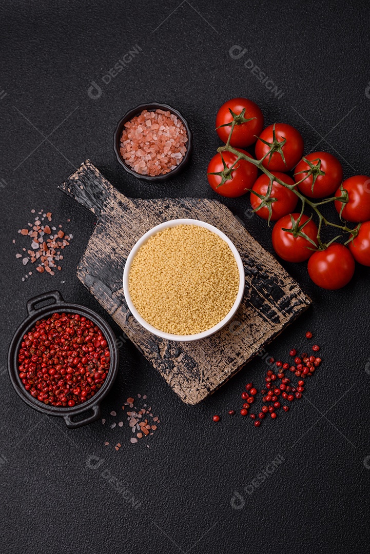 Grãos de cuscuz de mingau de trigo em um fundo escuro de concreto