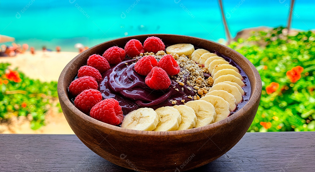 Belo creme de açai com acompanhamentos em uma tijela sobre fundo de uma praia