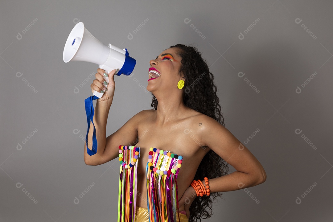 Linda morena do cabelo cacheado sorridente fantasiada segurando alto-falante sobre fundo isolado