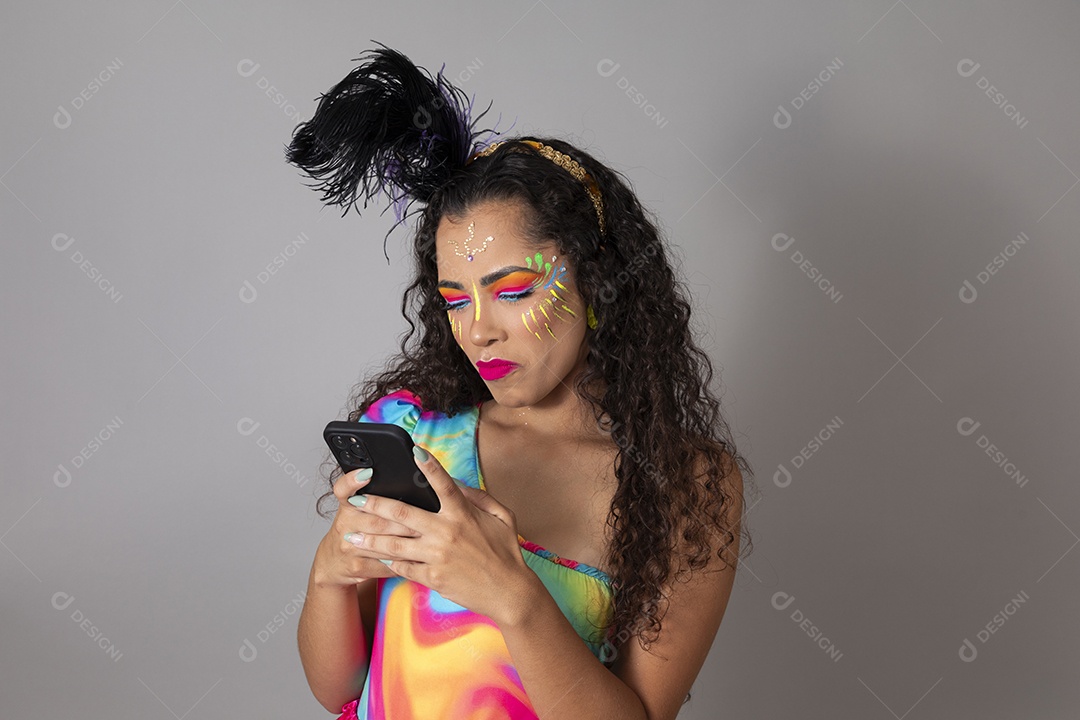 Linda morena do cabelo cacheado sorridente fantasiada segurando smartphone sobre fundo isolado