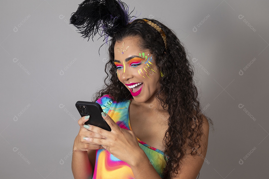 Linda morena do cabelo cacheado sorridente fantasiada segurando smartphone sobre fundo isolado