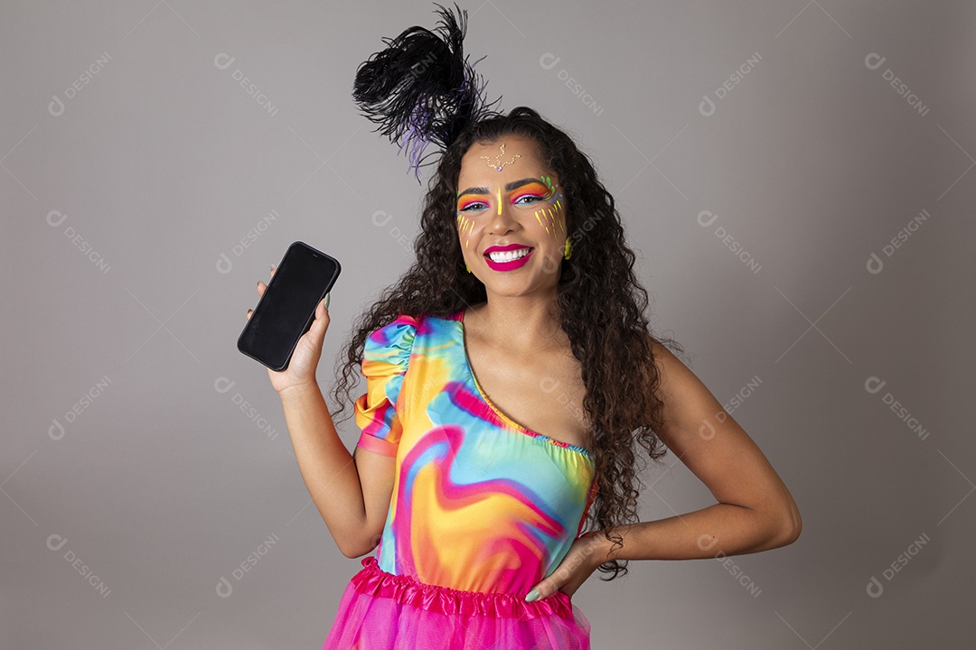 Linda morena do cabelo cacheado sorridente fantasiada segurando smartphone sobre fundo isolado