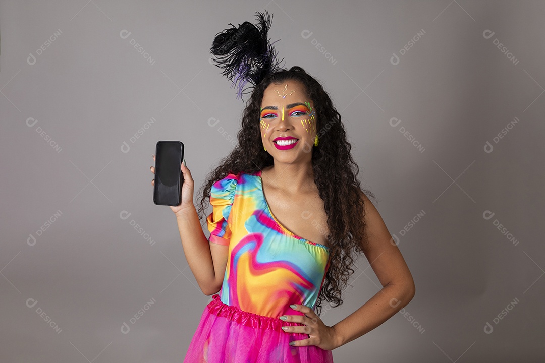 Linda morena do cabelo cacheado sorridente fantasiada segurando smartphone sobre fundo isolado